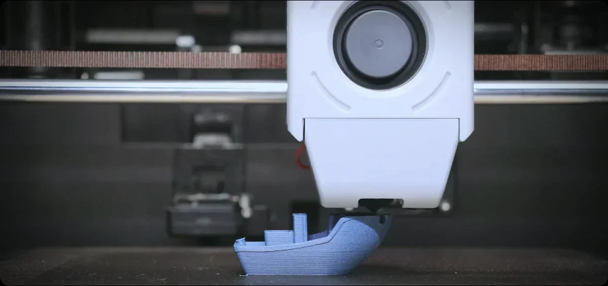 The 3D printer is printing a blue boat model